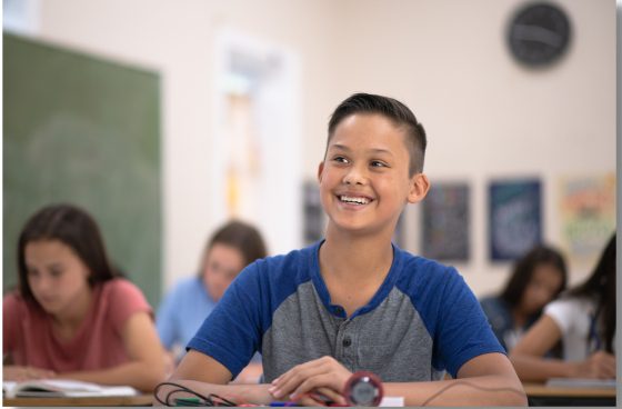 Un garçon dans une salle de classe sourit.